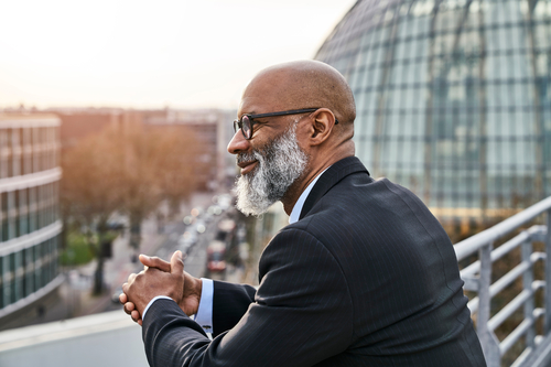 A senior businessman looking at the street below