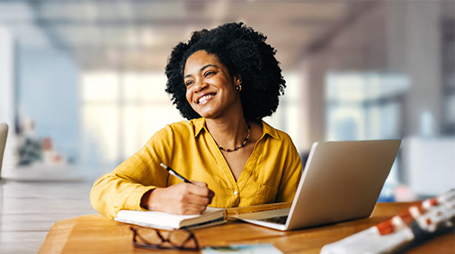 A businesswoman working in front of a laptop, holding a pen