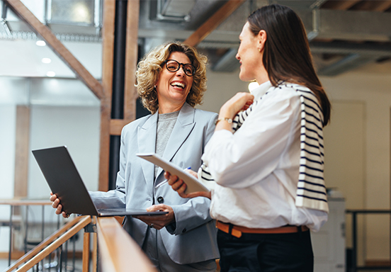 Two businesswomen talking in front of a laptop