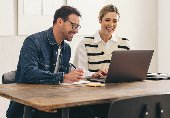 Two businesspeople talking in front of a laptop